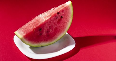 Stop motion creative animation slice of watermelon with seeds bite on red background. Summer dessert