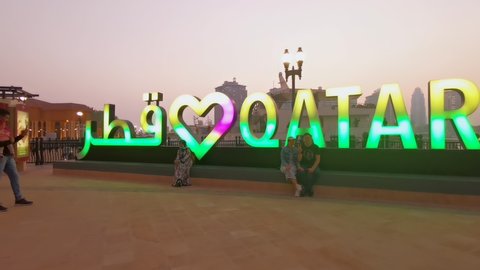 Doha, Qatar- July 31 2020: Porto Arabia  in The pearl Doha, Qatar sunset summer shot showing people walking on promenade and talking pictures beside illuminated Love QATAR sign