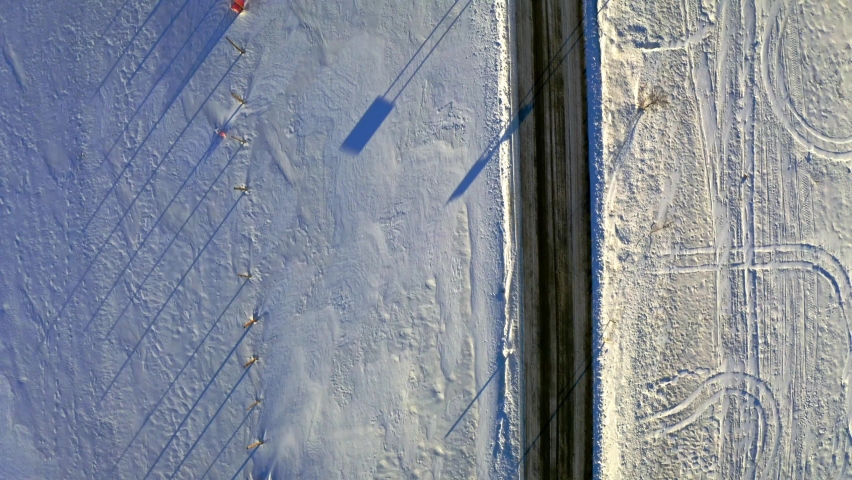 Snowy hay balls and black road in winter, aerial view, Poland