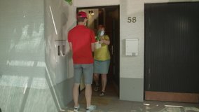 SLOW MOTION, CLOSE UP: Young courier delivers a parcel of fresh produce to senior lady during covid19 lockdown. Delivery guy wearing surgical mask hands elderly woman her box full of organic groceries - Powered by Shutterstock - Get 15% off with code: PIKWIZARD15