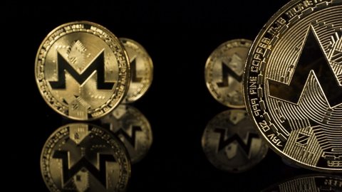 Macro close uping past golden monero crypto coins on reflective glass with a black background,ing backward cryptocurrency