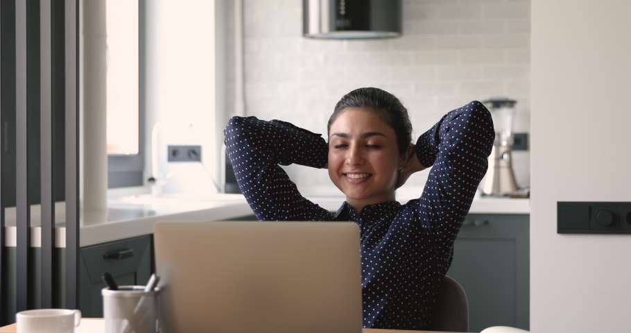 Indian satisfied woman sit at homeoffice accomplish work on laptop relaxing puts hands behind head. Lady daydreaming finished task feel peace of mind, think of future success and opportunities concept Royalty-Free Stock Footage #1058470576