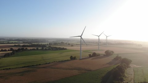 Morning aerial view shot of sunshine with lens flare of Aeolian wind turbine near french corn and wheat fields, Shadows of the propellers on the dirt ground. wind turbine wind turbine wind turbines