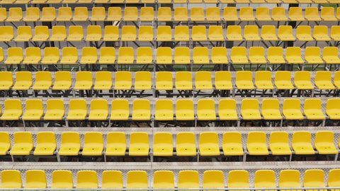 Aerial drone view of empty stadium or race track seats during coronavirus COVID-19 pandemic. Rows and yellow seats without viewers and spectators