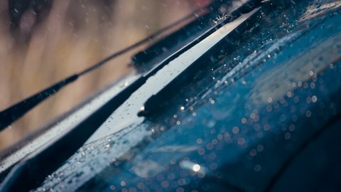 Raindrops fall on the windshield of the car and the brushes move to remove water. Closeup. Slow mo, slo mo, slow motion, high speed camera