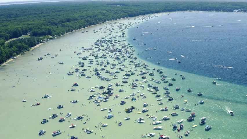 Aerial shot of Boats and Large Group People in shallow crystal clear Glacial Lake water on Sunny Summer Day Higgins Lake Michigan 4th of July