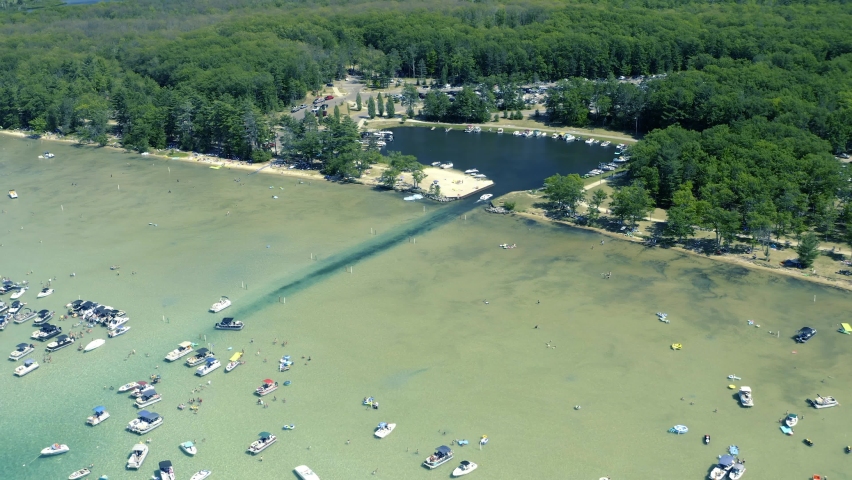 Aerial Pan Up Shot of Lagoon and small Lake with Boats and People in Shallow Waters of a Glacial Lake in Michigan