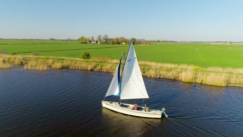 AERIAL WS Teenage girl (14-15) and teenage boy(16-17) sailing on river / Broek, Friesland, Netherlands
