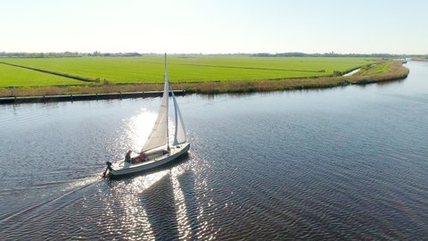 AERIAL WS Teenage girl (14-15) and teenage boy(16-17) sailing on river / Broek, Friesland, Netherlands