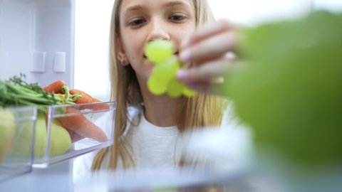 Kid Eating Grapes from Fridge. Hungry Child Eats Fresh Fruits in Refrigerator, Young Girl at Diet, Healthy Vegetables in Kitchen.