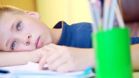 close-up portrait of a young cute boy, schoolboy lying at the table closes his eyes and falls asleep teaches lessons. studies homework sad and exhausted put head on book. teenager sleeps on notebooks  - Powered by Shutterstock - Get 15% off with code: PIKWIZARD15