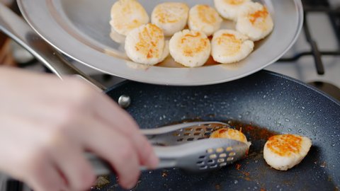 Collecting or taking away scallops from a frying pan using a tong in 4K. Concept of cooking scallops in a pan on a gas stove.