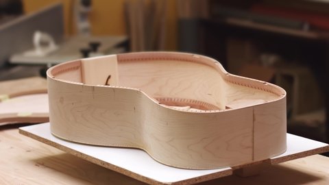 Young artisan making classical guitar in the workshop, time-lapse of guitar making