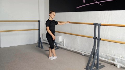 Dance training at a ballet school, for children, boys and girls. Hand on barre. Fourth position. The boy is dancing ballet.