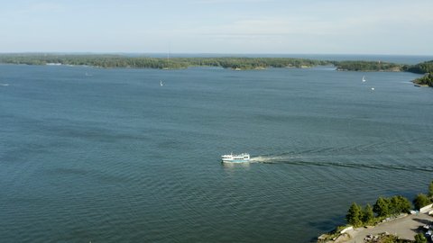 Aerial view of a passenger ferry,ing towards the Suomenlinna island, sunny, summer day, in Helsinki, Finland - pan, drone shot