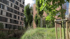 Footage of an urban park surrounding by apartment and industrial buildings in El Poblenou, Barcelona, Spain 