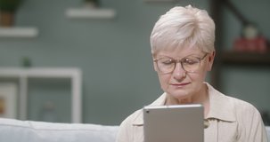 Caucasian woman in 50s using a tablet computer at home. Mature lady surfing the internet during self-isolation 4k footage