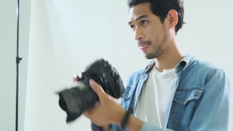 Young asian Professional photograher taking photos in his studio with cheerful and enjoy handheld shot