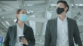 two asian businessman and businesswoman with face mask protection in international airport terminal conversation near information board business concept - Powered by Shutterstock - Get 15% off with code: PIKWIZARD15