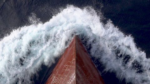 Red bow of a cargo ship breaking the waves.