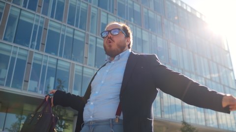 Successful businessman dancing and celebrating triumph outdoors. Funny overweight office employee dancing near business center excited about successful project