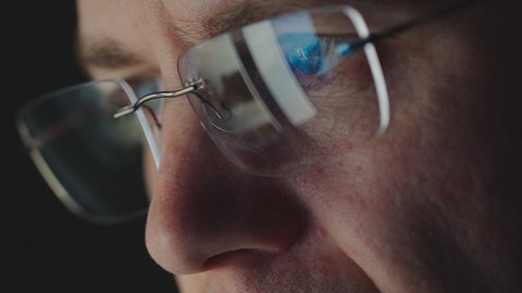 REFLECTION: Close Up of face of adult man in an eyeglasses looking a website