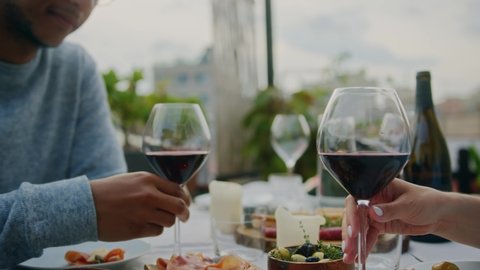 Romantic date dinner, Young happy couple in love drinking wine making cheers with glasses laughing and joking during dinner, interracial couple having raising a toast celebrating wedding anniversary