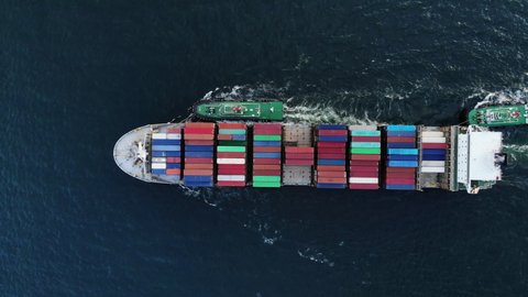 Aerial top view of cargo ship carrying container and running with tug boat for export  goods  from  cargo yard port to custom ocean concept freight shipping by ship .