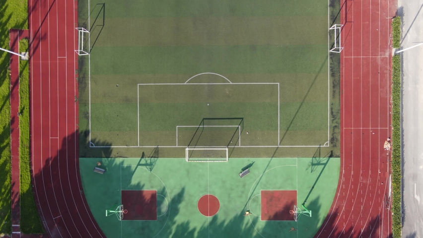 Aerial view drone flying close to empty soccer goal, football field during sunset in the stadium. No people view in summer, sports soccer recreation concept footage. Red racing track Shanghai China. Royalty-Free Stock Footage #1058527219