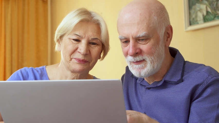 Senior couple at home using laptop. Retired family working on computer learning social media. Computer literacy among elderly people, active modern lifestyle on retirement | Shutterstock HD Video #1058527249