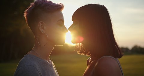 Two lesbian women kissing on sunset