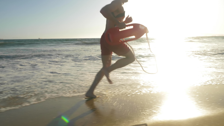 Male lifeguard running along the beach