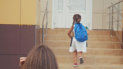 mom escorts her little daughter to school. happy family kid dream school concept. schoolgirl hurrying class for lesson to school. lifestyle kid and mom goodbye before school