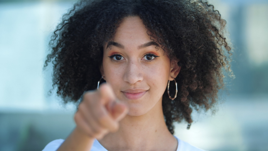 Beautiful African American girl pointing index finger at camera inviting with hand gesture. Young ethnic happy woman calling to showing something and speaking body language. Hey you, come here. | Shutterstock HD Video #1058538151