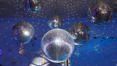 Several sparkling disco balls spinning with flashing lights during music band performance or dancing party. Party lights disco balls on blue background. Disco ball with bright rays, 4 k video
