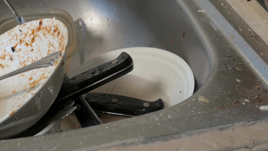 Sink full of dirty dishes.  Close up panning shot of many neglected dirty bowls and utensils.  Aftermath of cooking dinner in an unkempt kitchen.   Royalty-Free Stock Footage #1058546512