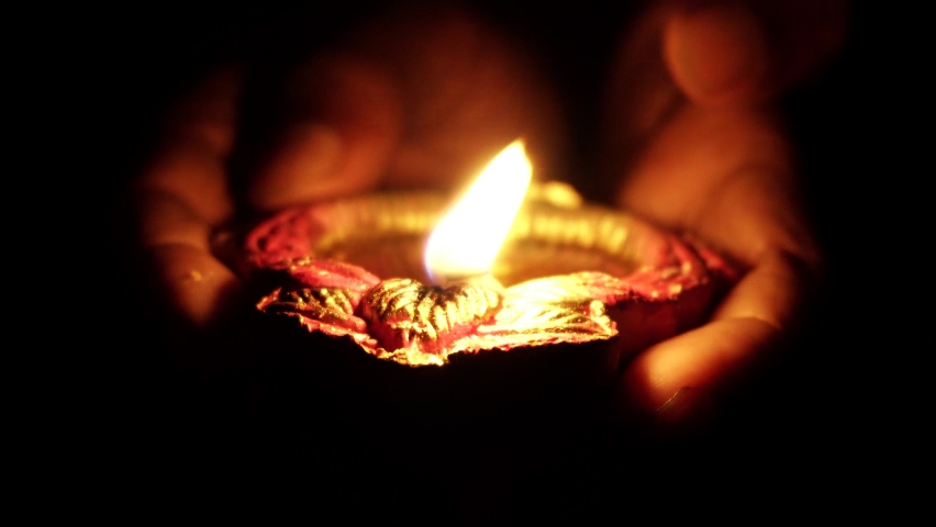 A person holding decorative colourful diya lamps lit during diwali festival.  Royalty-Free Stock Footage #1058550262
