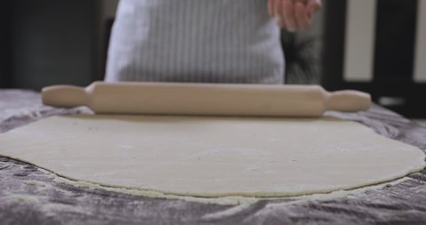 Baker kneading dough with rolling pin. Rolling dough for pizza or pasta.