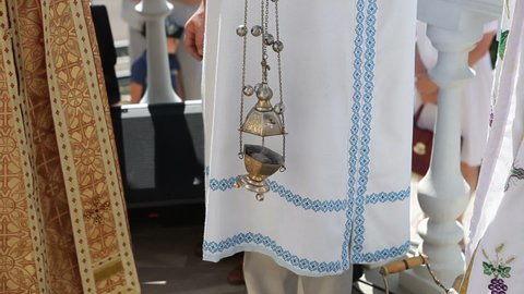 The priest holds a censer with burning incense in his hands.
