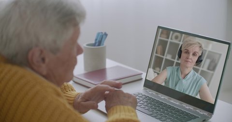 aged man is consulting with psychologist by online conference, staying home, using laptop with internet