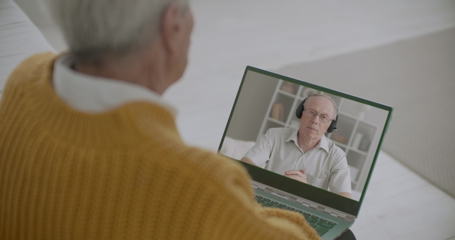 aged man is conducting online webinar and retired person is watching him on screen of his laptop, sitting at home Royalty-Free Stock Footage #1058550847