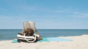 Anonymous woman from behind sunbathing on the beach and reading a book in summer day - Powered by Shutterstock - Get 15% off with code: PIKWIZARD15