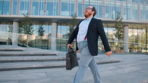 Joyful fat businessman dancing celebrating new career going to work outdoors. Funny overweight office manager dancing feeling happy about new startup project walking near business center