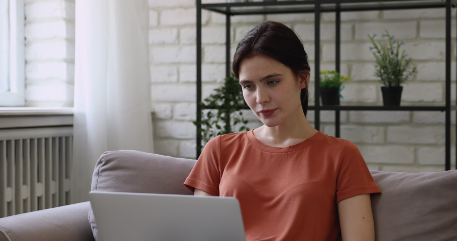 Pretty girl sit on sofa read email use laptop feel happy. Student got scholarship confirmation, gambler win money on-line lottery victory, great news sincere reaction, candid emotions, success concept Royalty-Free Stock Footage #1058571238