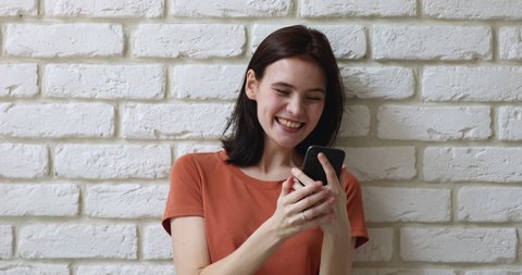 Girl pose against white brick wall hold smart phone read great news feels happy jumps scream with joy. Lottery win, student got scholarship. Invitation and special offer receive, sale discount concept