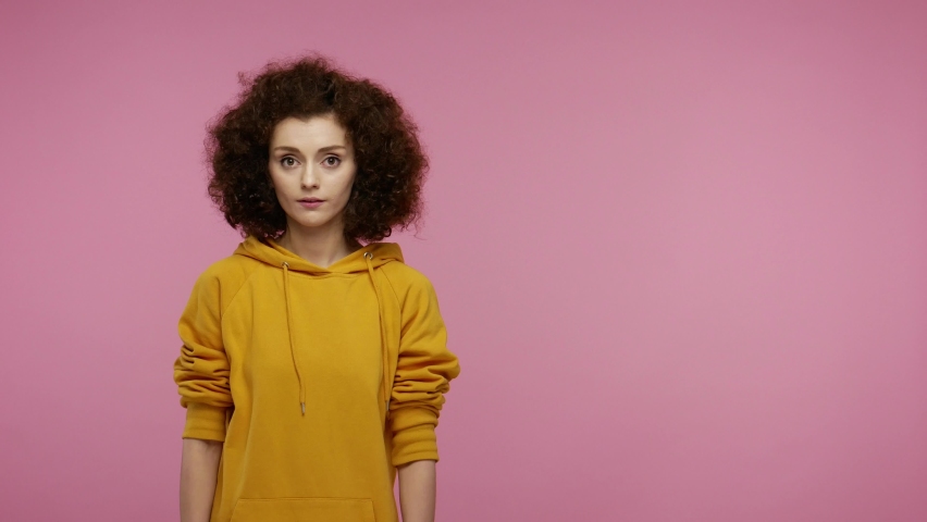 Amazed young woman afro hairstyle in hoodie pointing empty place on her palm, copy space advertising area on hand, expressing excited surprised emotions. indoor studio shot isolated on pink background Royalty-Free Stock Footage #1058576398