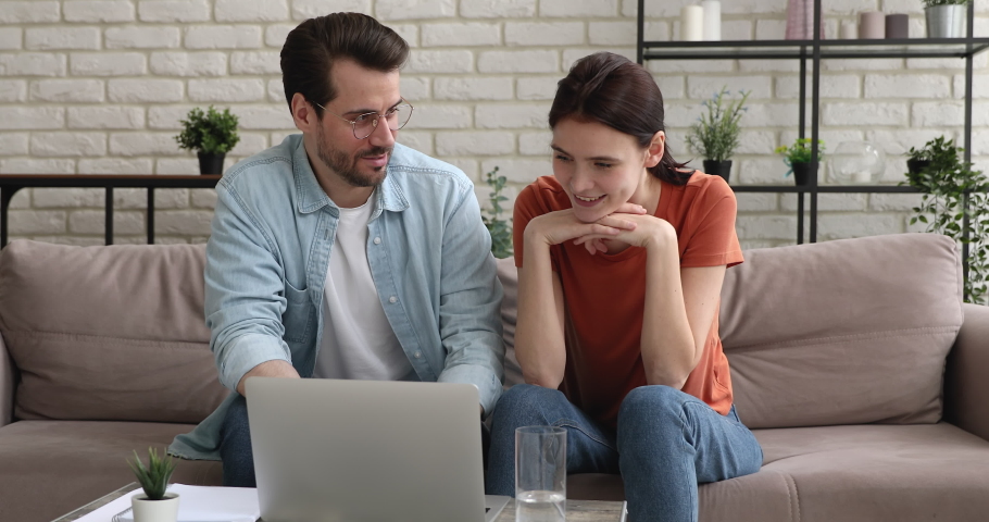Couple sit on sofa use laptop read fantastic news e-mail scream with joy celebrate victory feels rejoice. Online auction, betting and lottery winners. Notification from bank about loan approve concept Royalty-Free Stock Footage #1058581237