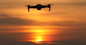 A silhouette of a drone flying in a beautiful sunset, drone in the sunset sky,A drone taking pictures of aerial views.