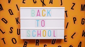 BACK TO SCHOOL sign on a letter board with letters being animated around. Orange background. - Powered by Shutterstock - Get 15% off with code: PIKWIZARD15