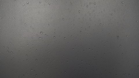 Water droplet on frosted glass wall or wet translucent window by shower person with people shadow or rain water drop and splashes in bathroom or shower room with white light for texture background 4K